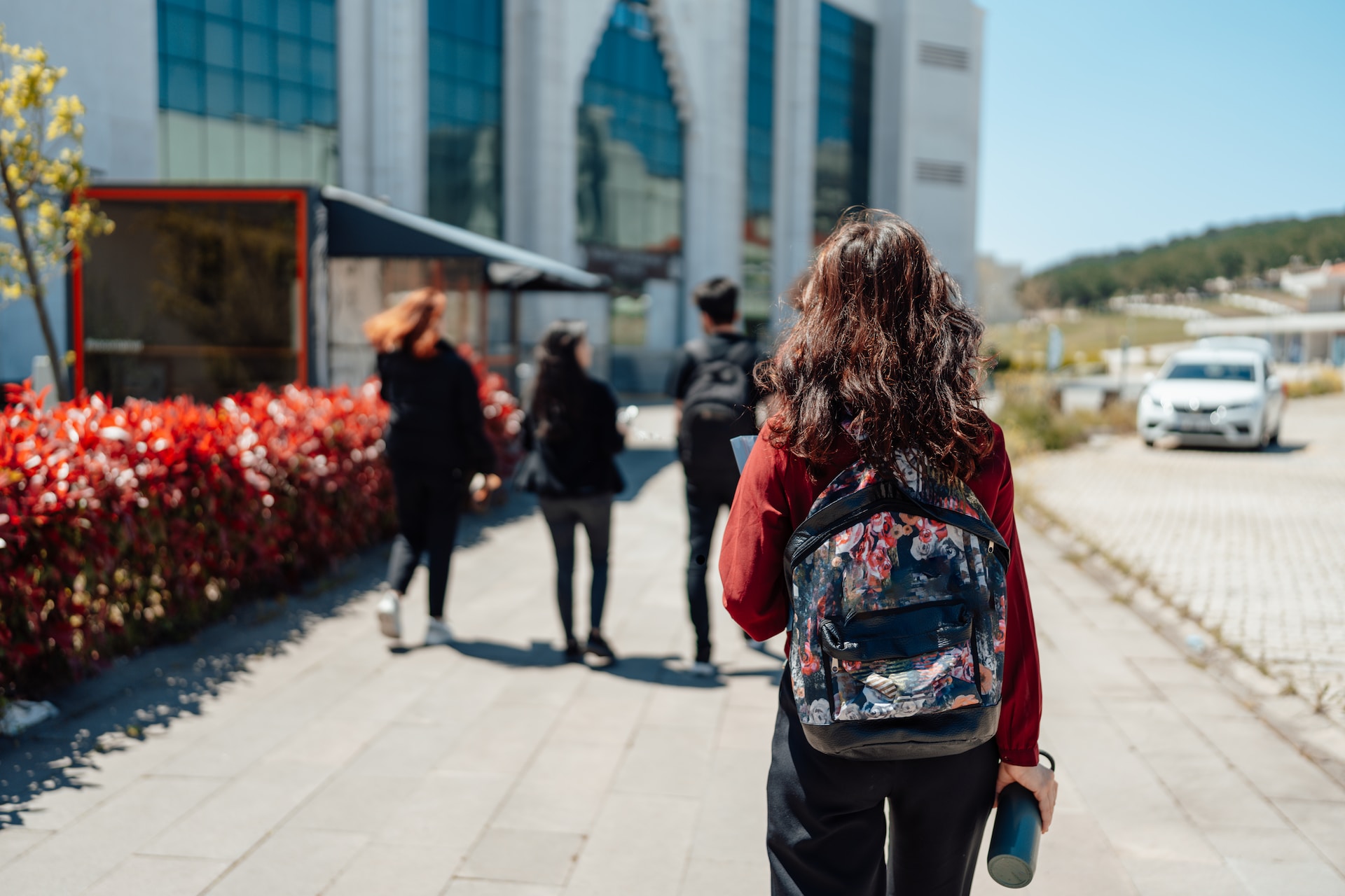 student wearing bookbag and holding water bottle walking outside