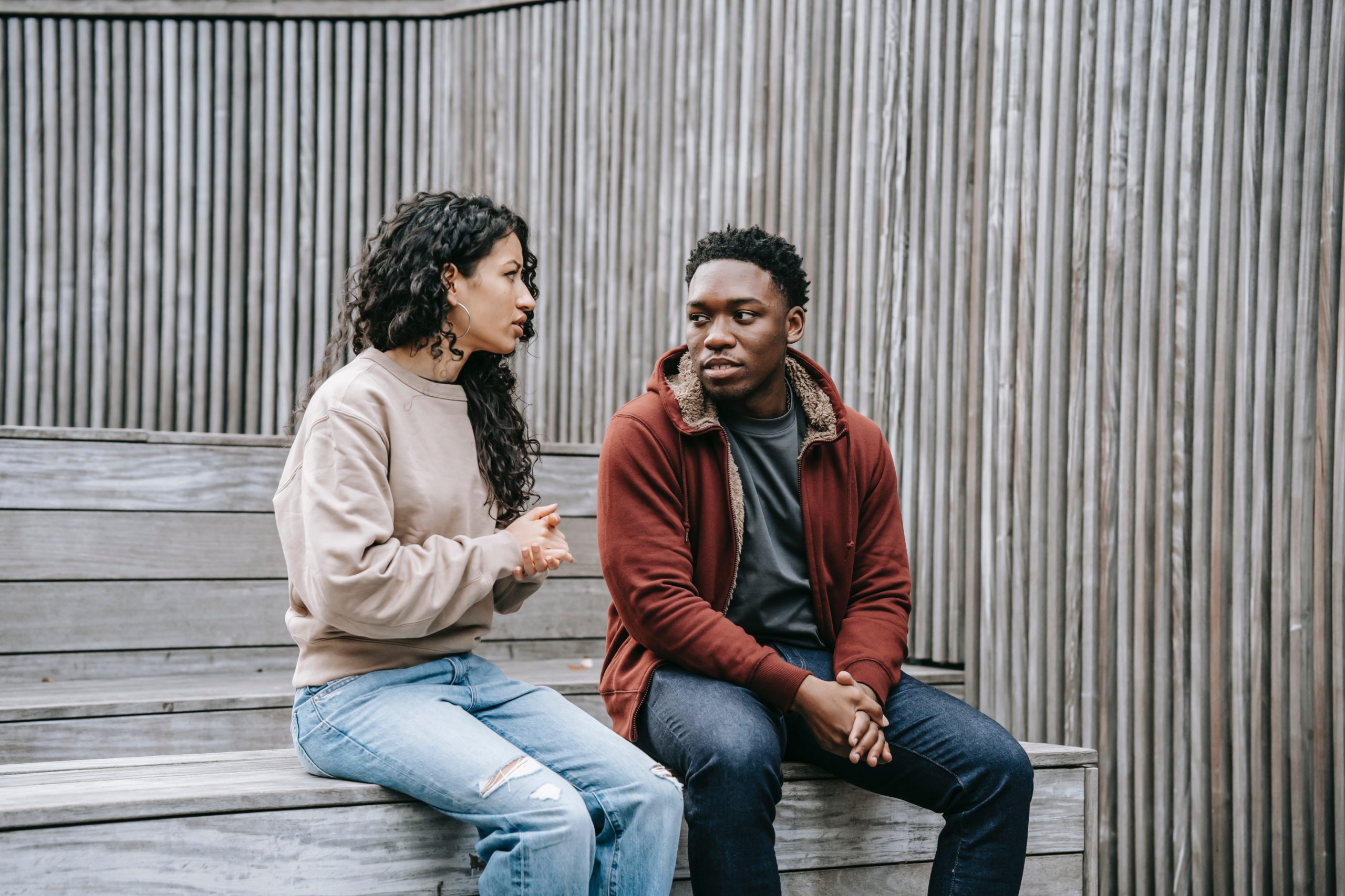 A couple sitting on a bench outside having a serious conversation