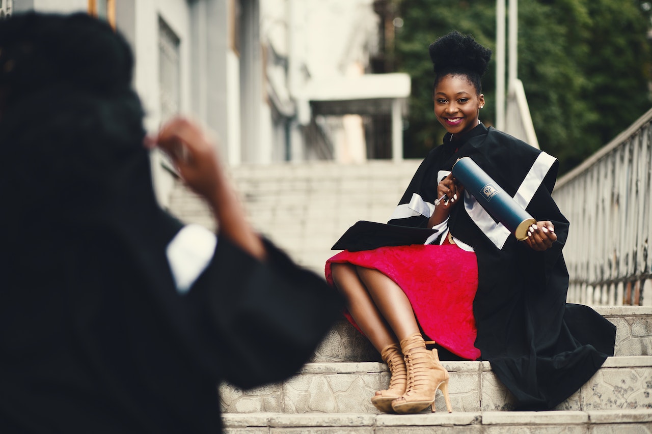 smiling student sitting on steps holding diploma
