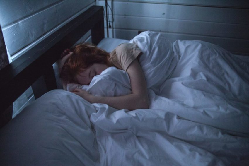 young adult woman sleep in bed in dark room