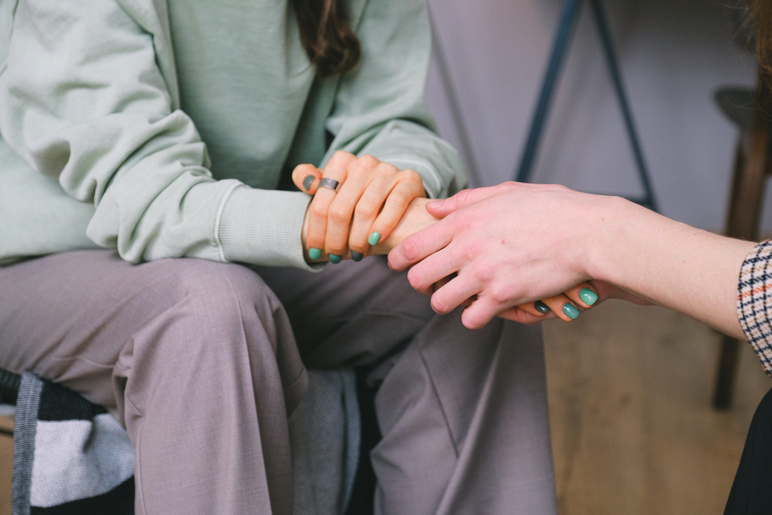 a person comforting another person by holding their hand in between their hands